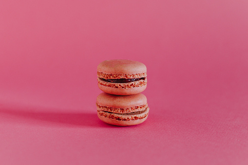 Tasty french macarons on a bright pink background. Place for text.
