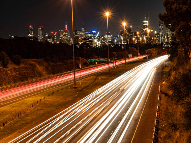 istock Multi lane free way with light trails and urban skyline 1591086488