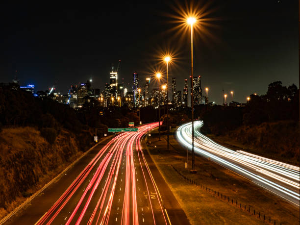 istock Multi lane free way with light trails and urban skyline 1591086492