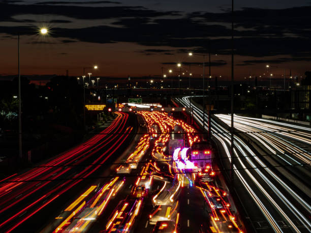 istock Multi lane free way with light trails and urban skyline 1591087003