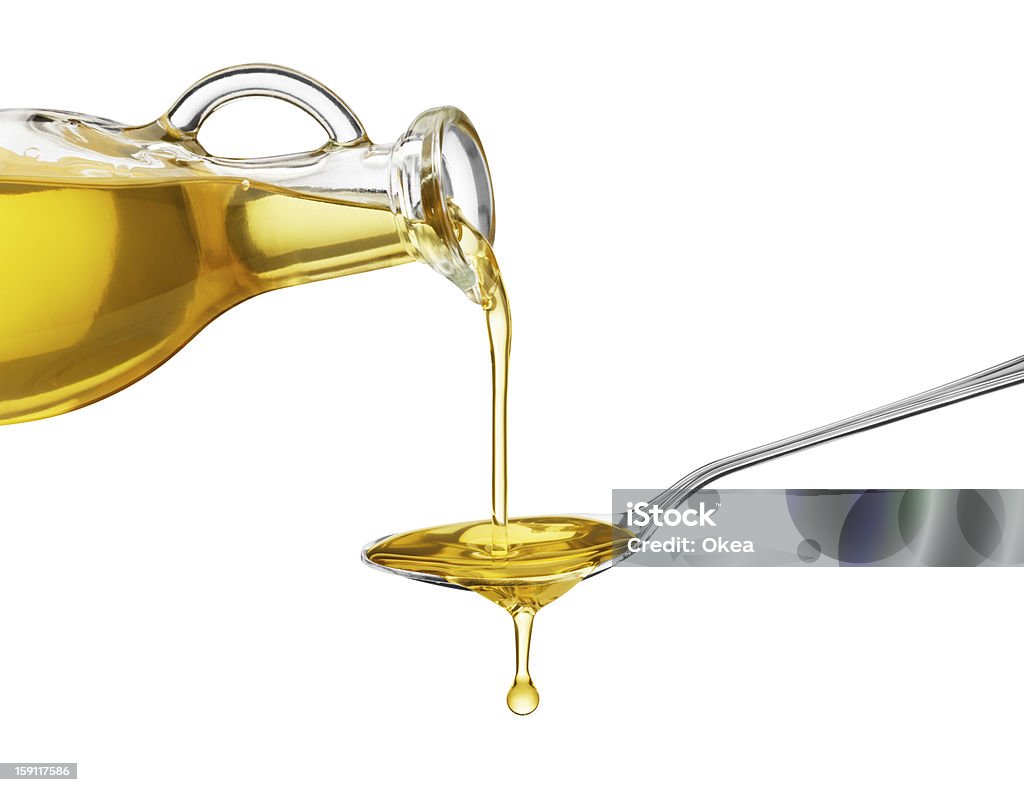 Oil being poured from a large bottle onto a spoon pouring oil on spoon from glass bottle Olive Oil Stock Photo