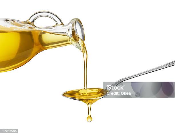 Oil Being Poured From A Large Bottle Onto A Spoon Stock Photo - Download Image Now - Olive Oil, Cooking Oil, Pouring