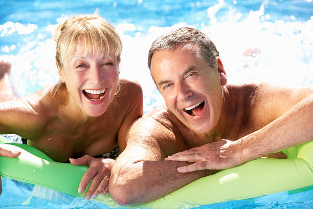 istock Smiling senior couple having fun in swimming pool 159120112
