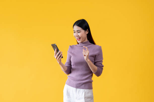 istock A pretty Asian woman is using her smartphone, using mobile apps. isolated yellow background 1591209542