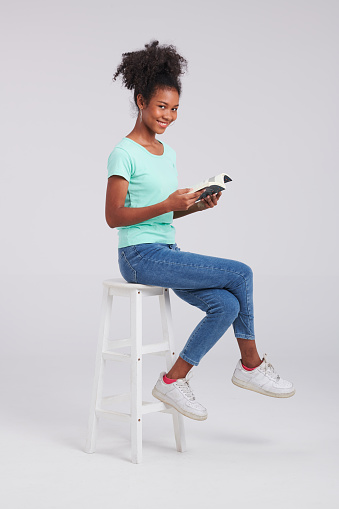 Exuding chair chic, an American woman wears mint shirt and blue jeans, adding allure to the studio fashion capture.