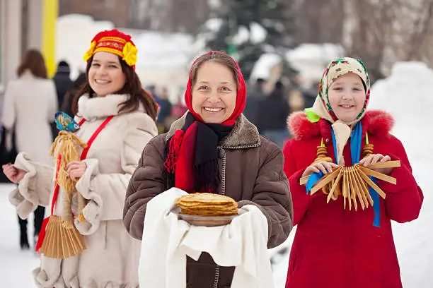 women in russian traditional clothes with pancake and round cracknel during  Shrovetide