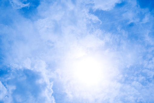 sun on blue sky with white clouds 