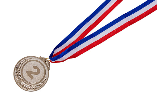 A close up of a gold medal engraved with 2024 on it.  A red, white, and blue ribbon is attached to the medal that rests on a white background.