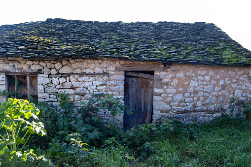 Traditional stone crofter's cottage with stones weighing down the thatched roof in a picturesque summer landscape of green pasture and rolling hills overlooking the mountains of the Western Isles deep in the Highlands of Scotland, UK. ProPhoto RGB profile for maximum color fidelity and gamut.