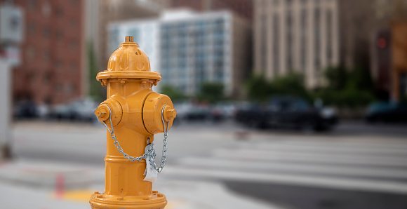 A vibrant red fire hydrant stands prominently against a neutral urban background. The silver top contrasts with the bright red body, emphasizing its functionality and importance.