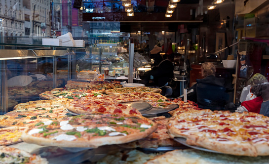 Pizza assortment in a pizza shop display, close up. Delicious Italian street food.