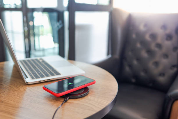 istock Charging mobile phone battery with wireless charging device in the table. Smartphone charging on a charging pad. Mobile phone near wireless charger Modern lifestyle concept. 1591349598