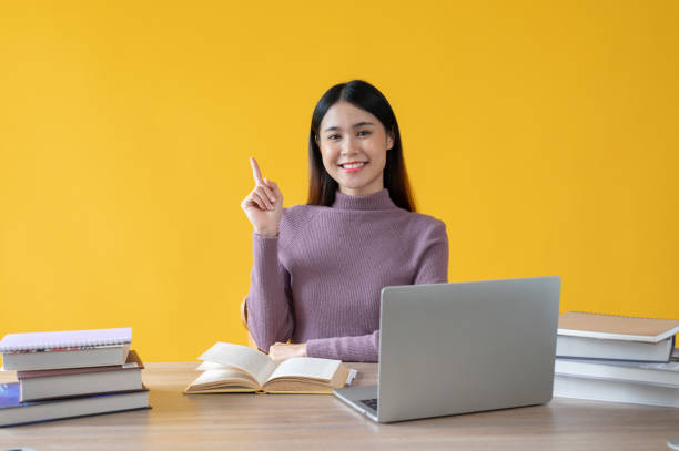 istock A beautiful Asian female college student sits at her study table with finger pointing up 1591353904