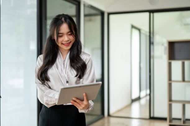istock A beautiful Asian businesswoman is using her tablet at an office corridor. 1591364308