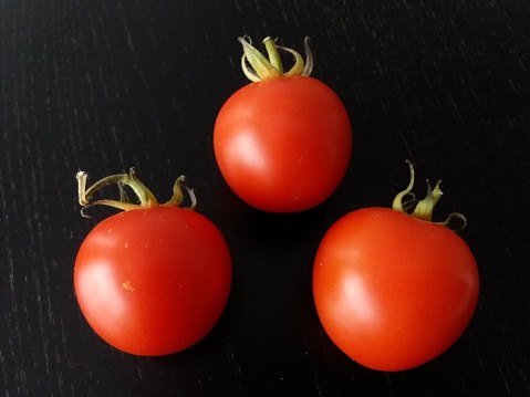 Three small tomatoes on black kitchen table
