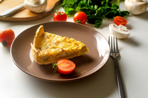 Quiche â open tart pie with chicken meat, champignons mushrooms, onion and cheese on white table. Homemade pie, cut into pieces. French cuisine