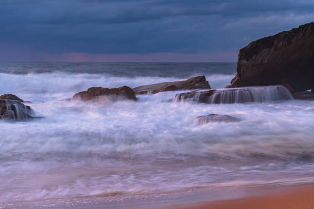 istock Sunrise seascape with low clouds and waves 1591423156