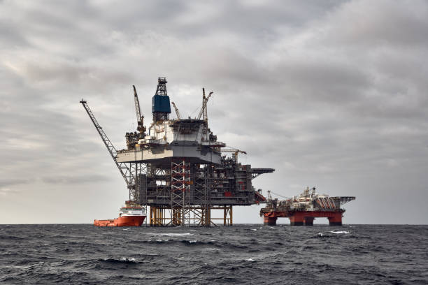 istock Offshore oil and gas platform with supply vessel doing cargo operations. 1591456081