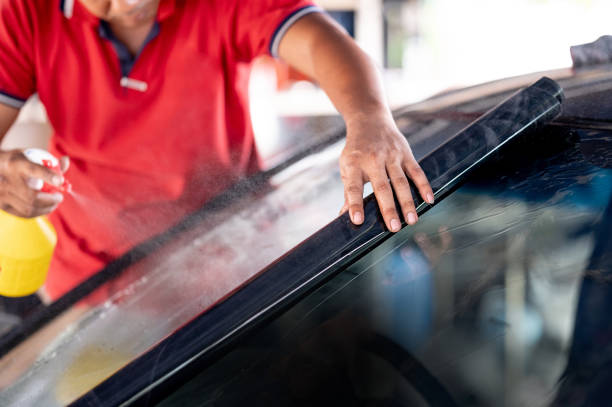 istock Rolling and spraying car film on front windscreen glass 1591458700