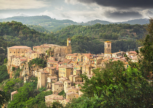 The image showcases Sorano, an ancient Etruscan small town in Tuscany, Italy. Its timeless charm emanates from the narrow cobbled streets, centuries-old stone buildings, and terracotta roofs. 
 Perched on a rocky outcrop, Sorano offers panoramic views of rolling hills and lush greenery. Its well-preserved medieval architecture evokes a sense of history. This image captures Sorano's allure, blending ancient heritage and Tuscany's serene beauty, making it a captivating destination for history enthusiasts and nature lovers alike.