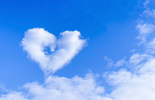 Heart-shaped cloud in blue sky with text space