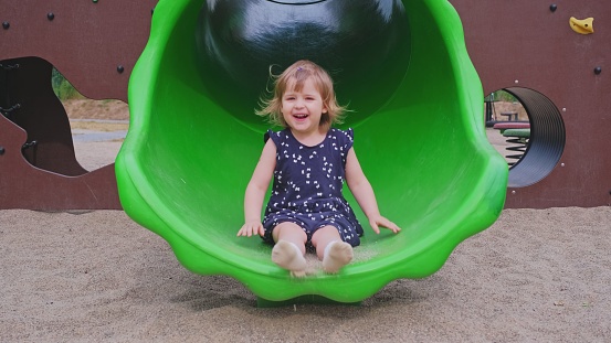 Happy Cute Caucasian Toddler Child Girl Playing on Modern Playground Slide