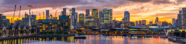 london canary wharf docklands skyscrapers glittering sunset waterfront developments panorama - millennium dome imagens e fotografias de stock