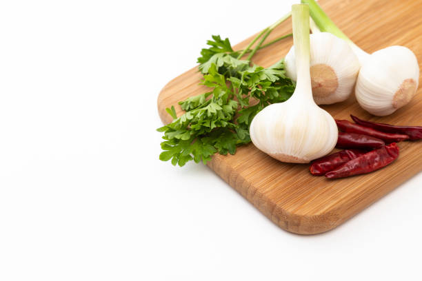 Fresh vegetables on the table. Food background. A bunch of parsley, chopped red pepper, garlic and spices on a wooden chopping Board. Ingredients for pickling or salads
