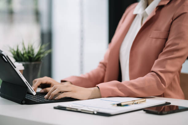 istock Business women calculate and analyzing graph document financial with laptop  in office. 1591523090