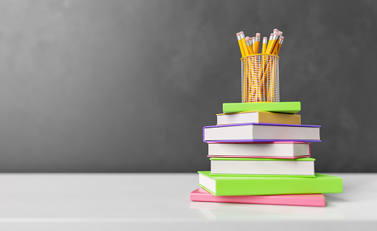 Stack of colorful bounded books on white table with pencils