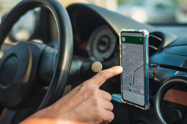 istock Man driving while using the mapping app on his smartphone to find his location. using a phone as a navigation device in a car 1591555935