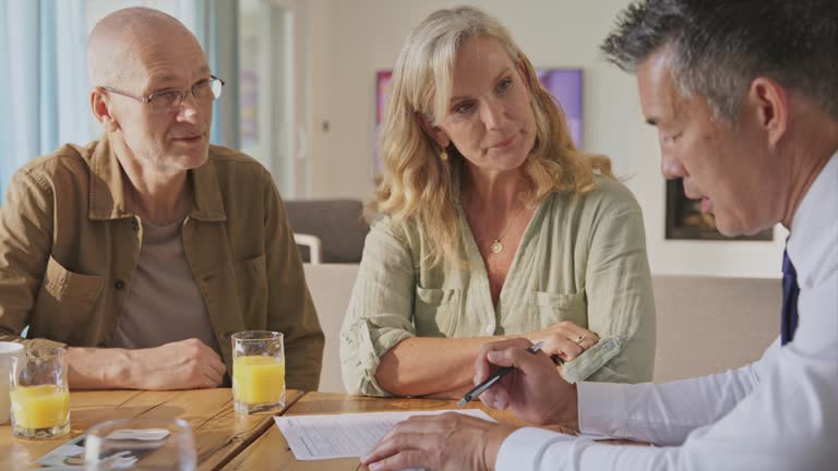 Male personal financial advisor talking to a male and female client in their home