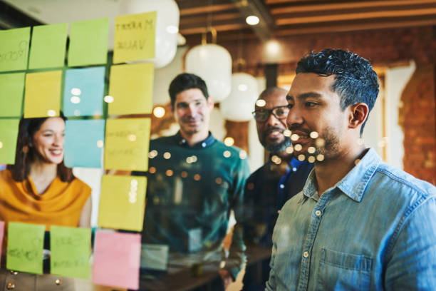 istock Project executive looking at sticky notes on glass wall in office 1591572472