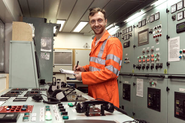 istock Young offshore marine engineer officer checking equipment in engine control room with smiling face. 1591582400