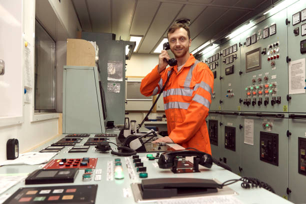 istock Young Offshore engineer communicating by telephone in engine control room. 1591582411
