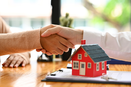 real estate agent or landlord shaking hands with client after sign agreement or sale purchase contract..
