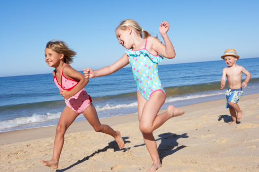 Three Children Running Along Beach Having Fun