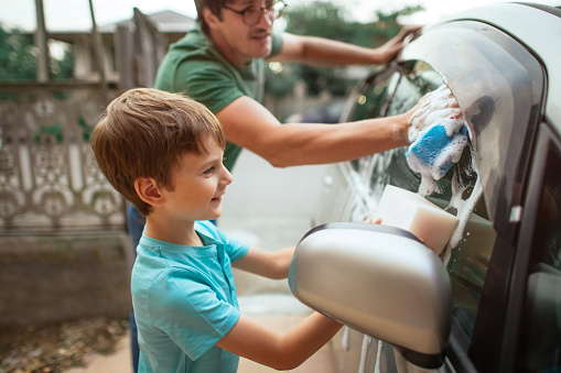 Family washing car outdoors in summer evening