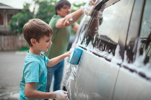 Family washing car outdoors in summer evening