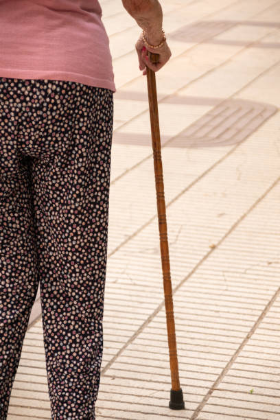 istock Madrid/Spain; August 4th 2023: An elderly persons lower body and a walking cane on a tiled floor with white and beige stripes 1591626612