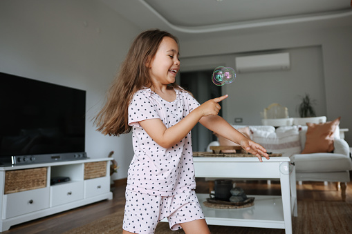 A little girl runs and plays with a small soap bubble