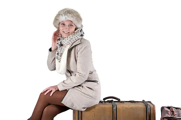 young woman in winterclothes with suitcases, isolated on white background