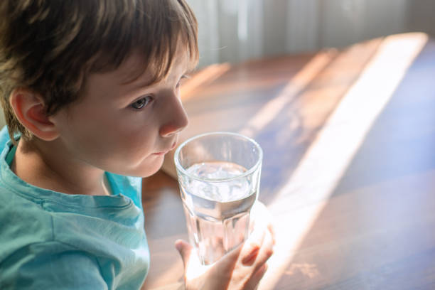 istock Little boy drinking a glass of water 1591641061