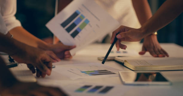 istock Business people, meeting or hands with graphs paperwork for analysis, data analytics or report review. Teamwork, collaboration closeup or employees planning charts statistics or documents at night 1591653290