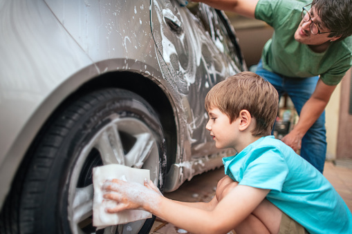 Family washing car outdoors in summer evening