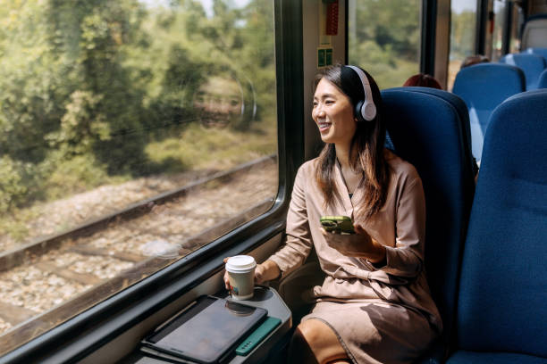 istock Young smiling beautiful woman using mobile phone while riding in a train 1591657873