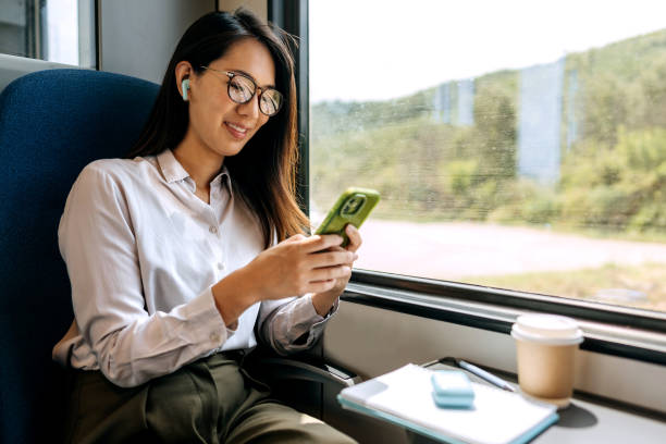 istock Young smiling businesswoman using mobile phone while riding i a train 1591658260