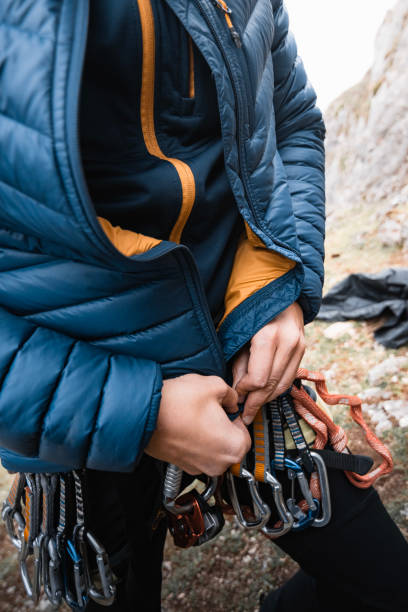 istock Man with harness and climbing gear adjusting his equipment and down jacket while climbing 1591661532