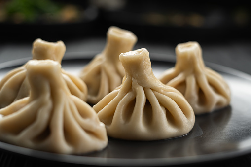 National Georgian cuisine concept. Khinkali with meat on plate. Big khinkali on a wooden board, close-up.