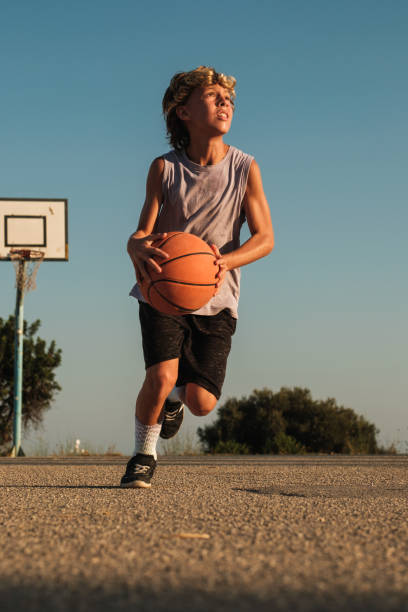 istock Active boy playing with basketball on court 1591662646